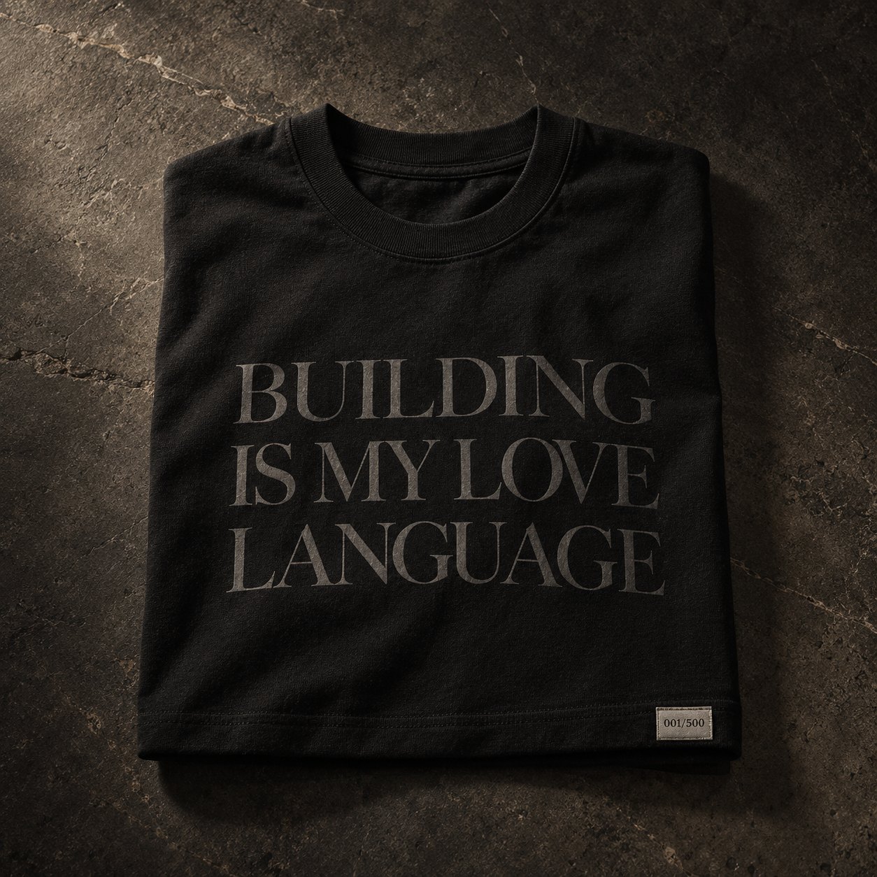Folded black tee with tonal serif print and numbered label